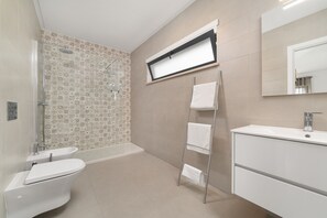 A modern bathroom with a shower, toilet, sink, and a towel rack.