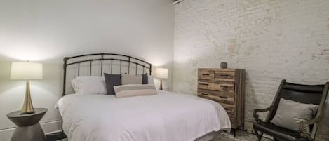 Un dormitorio con cama, lámparas de noche, cómoda y una silla.