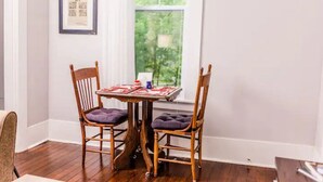 Un comedor con una mesa de madera y dos sillas, un cuadro en la pared y una ventana con vistas a zonas verdes.