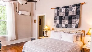 Un dormitorio con una cama grande, colcha, lámpara y ventana.