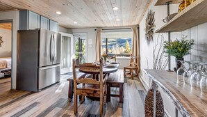 A modern kitchen with wooden flooring, stainless steel appliances, and a dining area with a wooden table and chairs.