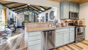 A spacious kitchen with granite countertops, stainless steel appliances, and light blue cabinets.