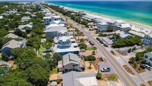 An aerial view of a coastal residential area with houses, a beach, and a clear sky.