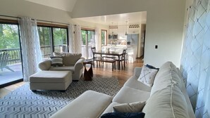 A spacious living area with a high ceiling and exposed wooden beams, a dining area, and a kitchen. - Modern open concept house w/Lake George views, private beach- 5 mins to village  (Lake George)