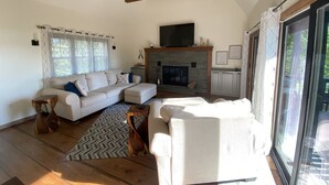 A spacious living room with a fireplace, a sofa set, and a large window. - Modern open concept house w/Lake George views, private beach- 5 mins to village  (Lake George)