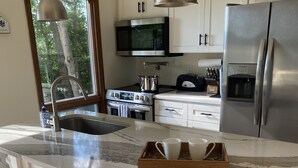 A modern kitchen with a large island, stainless steel appliances, and bar stools. - Modern open concept house w/Lake George views, private beach- 5 mins to village  (Lake George)