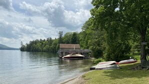 A lakeside property with a dock, a house, and boats. - Modern open concept house w/Lake George views, private beach- 5 mins to village  (Lake George)