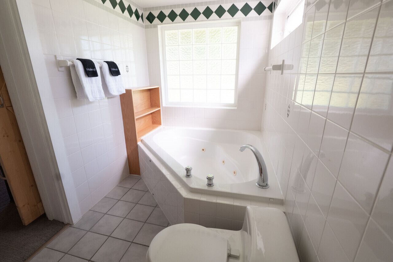 A bathroom with a bathtub, a toilet, and a window.