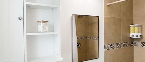 A bathroom with a white sink, mirror, and shelves.
