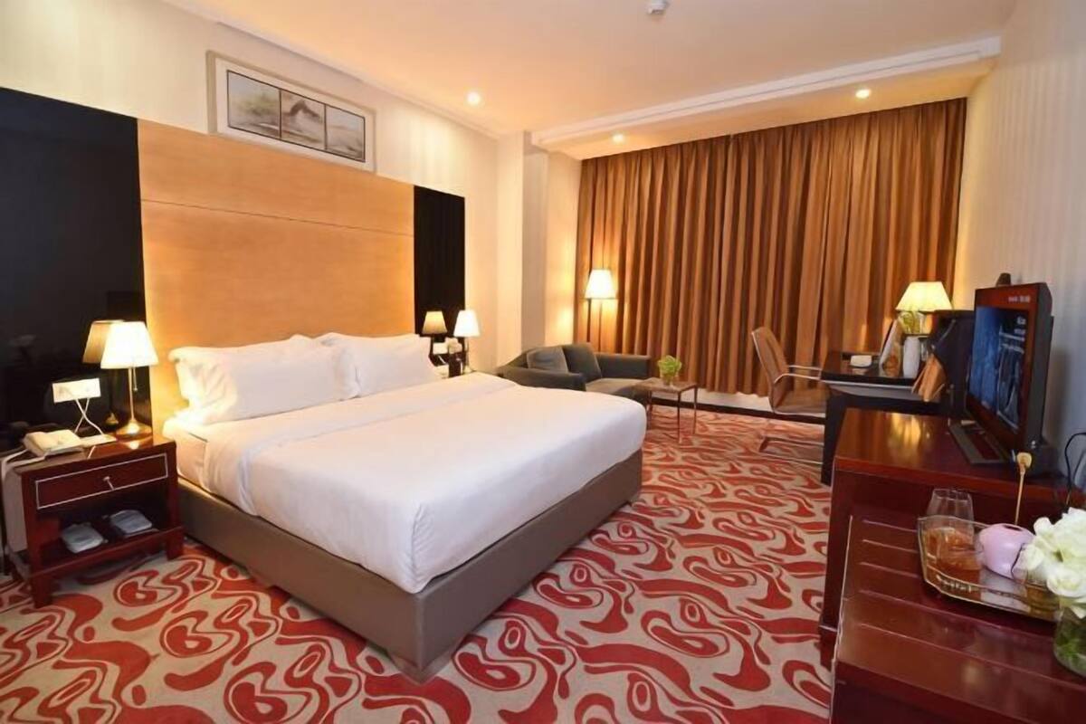 A hotel room with a large bed, a desk with a computer, a TV, and a chair.