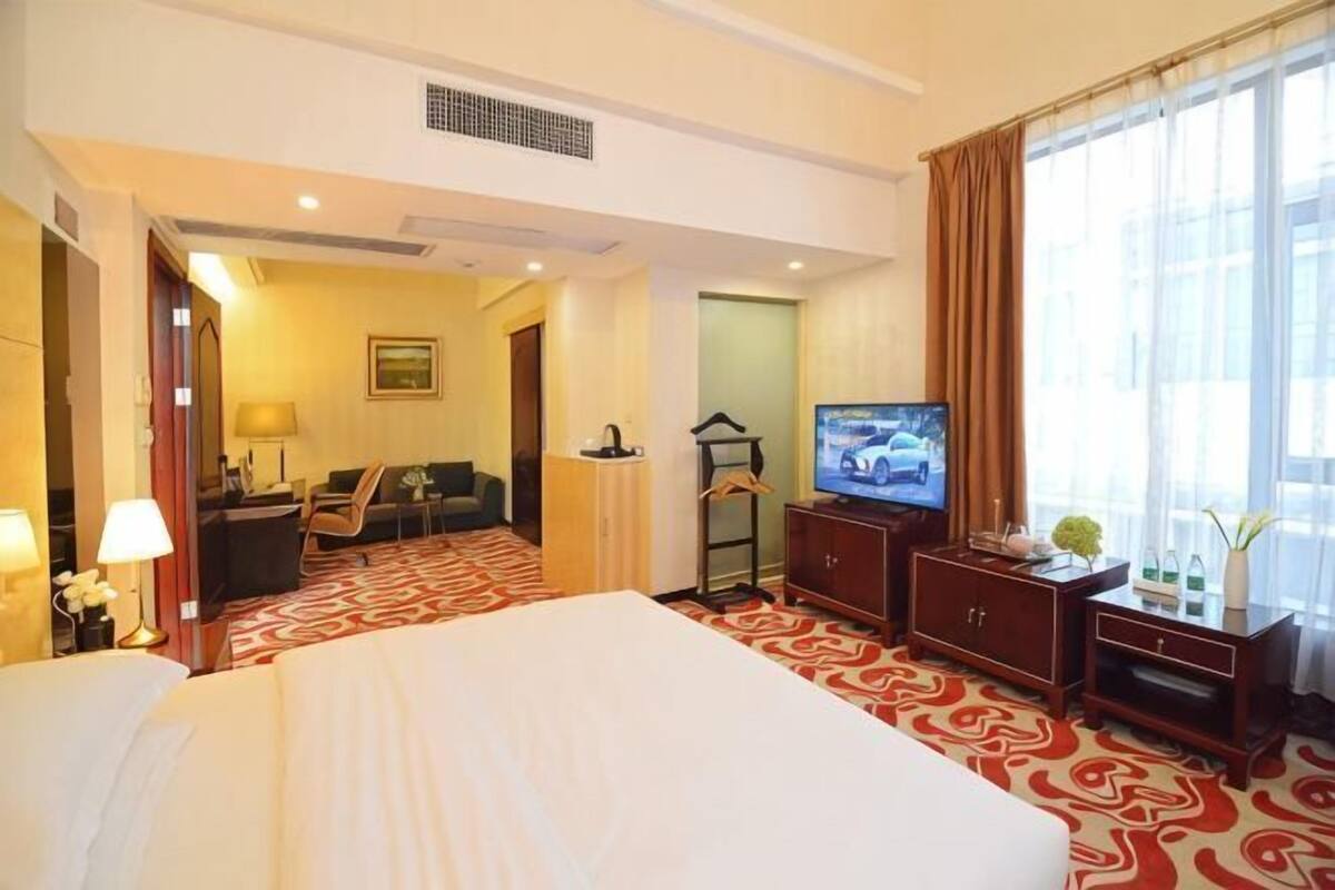 A hotel room with a large bed, a television, a desk, and a chair.
