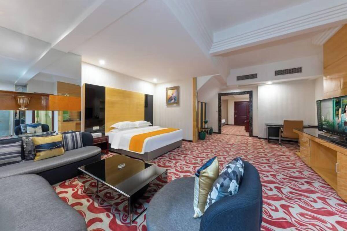 A hotel room with a bed, sofa, TV, and a desk.