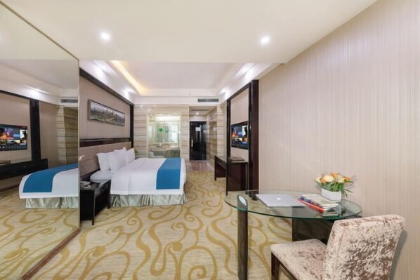 A hotel room with a bed, a glass table, a chair, and a mirror.