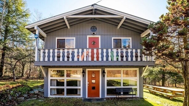 A two-story house with a balcony, a front door, and a mailbox.