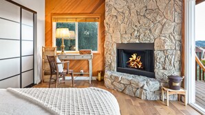 A cozy room with a stone fireplace, wooden ceiling, and a view of the outdoors.