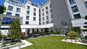A modern hotel with a courtyard featuring outdoor seating and a well-maintained lawn. - Aniroc Signature Hotel (Arad)