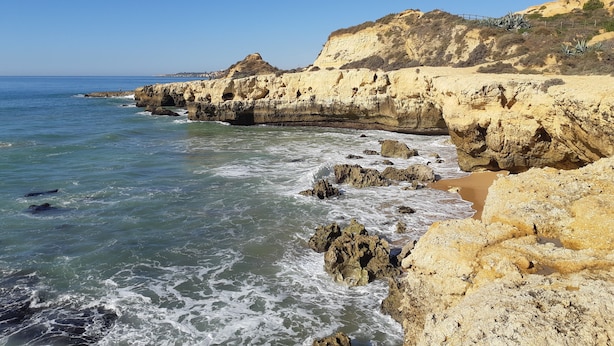 A coastal landscape with rocky cliffs and a beach. - Spacious Studio Apartment overlooking garden and pool area (Albufeira)