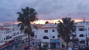 A coastal town with white buildings, palm trees, and a sunset. - Spacious Studio Apartment overlooking garden and pool area (Albufeira)