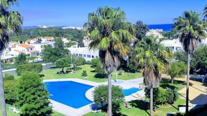 A resort with a swimming pool, palm trees, and a view of the sea. - Spacious Studio Apartment overlooking garden and pool area (Albufeira)