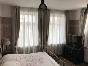 Une chambre à coucher avec un lit, une télévision, une commode et des rideaux.