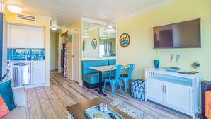 Un espacio habitable compacto con kitchenette, comedor y asientos.