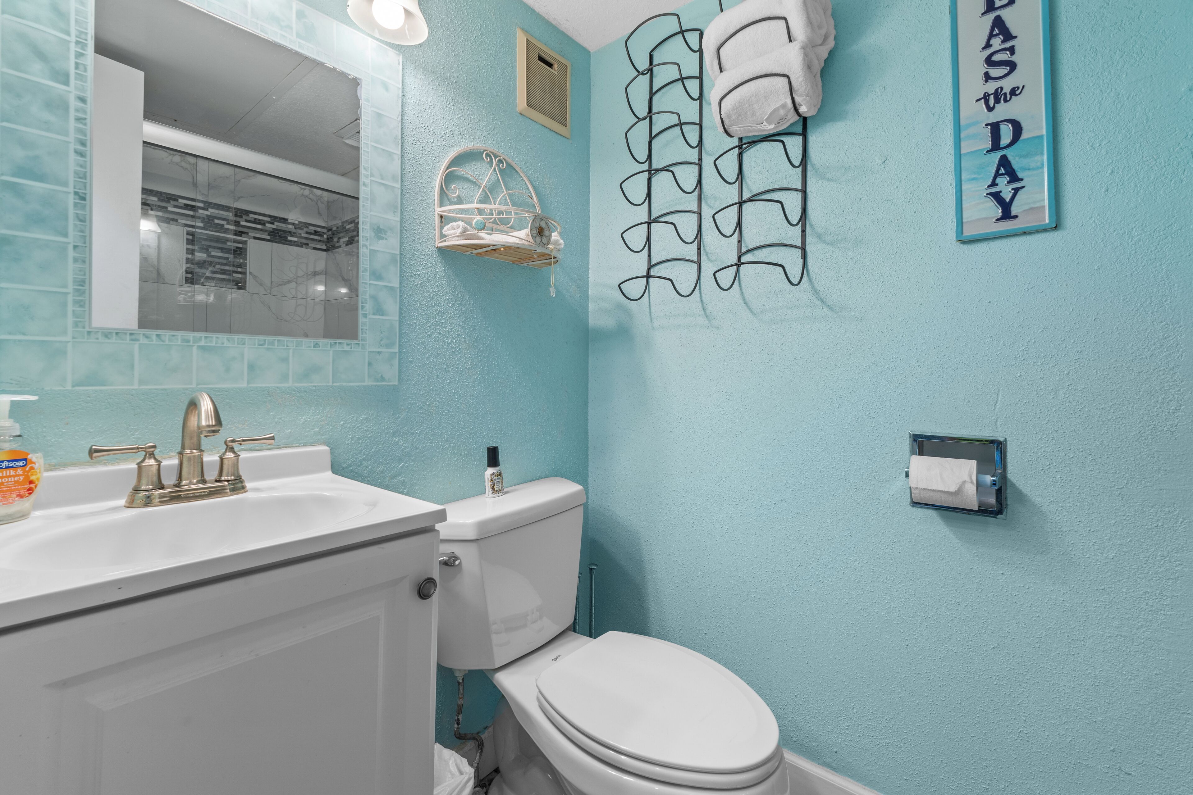 A bathroom with a white sink, a toilet, a towel rack, and a 'TASDAY' sign.