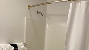 Un baño moderno con ducha a nivel, barras de apoyo y un perchero con toallas blancas.