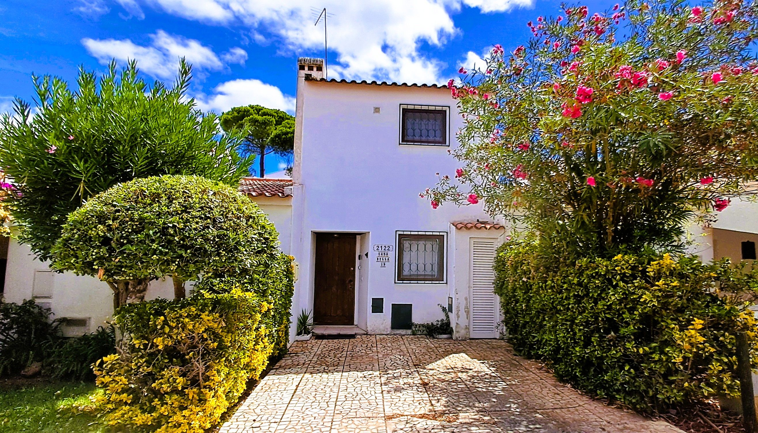 A two-story house with a tiled entrance, a small window with bars, and a door.