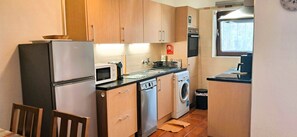 Cocina compacta con refrigerador, microondas, lavavajillas y lavadora.