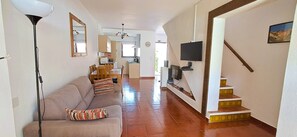 Un soggiorno con un divano, una TV montata a parete e una scala che conduce in un'altra stanza.