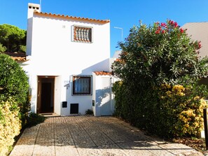 A white building with a tiled roof, a door, and a window with a metal grille.