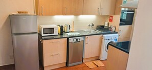 A compact kitchen with a refrigerator, microwave, dishwasher, and washing machine. - Villa Bella 200 meters from Falésia Beach by Urban Hypotenuse (Albufeira)