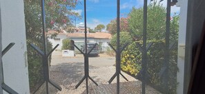 A view through a mesh screen with a paved area, a parked car, and some greenery. - Villa Bella 200 meters from Falésia Beach by Urban Hypotenuse (Albufeira)