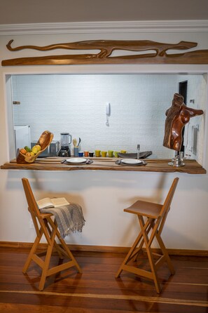 Cozinha com bancada de madeira, duas cadeiras de madeira e painel de tijolos brancos.