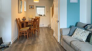 A cozy living room with a sofa and a dining area with a table and chairs. - 2 bedroom accommodation in Combe Martin (Combe Martin)