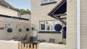 A residential building with a beige exterior, a wooden fence, and a small patio area with a table and chairs. - 2 bedroom accommodation in Combe Martin (Combe Martin)