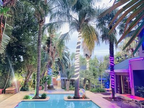 Relax by the serene pool surrounded by lush tropical vegetation and tall palm trees.
