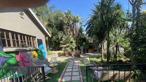 A garden with a paved pathway, outdoor seating, and a mural on a building.