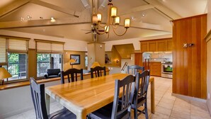 A spacious dining area with a wooden table and chairs, a chandelier, and a kitchen in the background. - Soda Springs 3 Bedroom Townhome (Keystone)