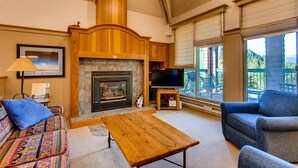 A cozy living room with a fireplace, a sofa, a coffee table, and a TV. - Soda Springs 3 Bedroom Townhome (Keystone)