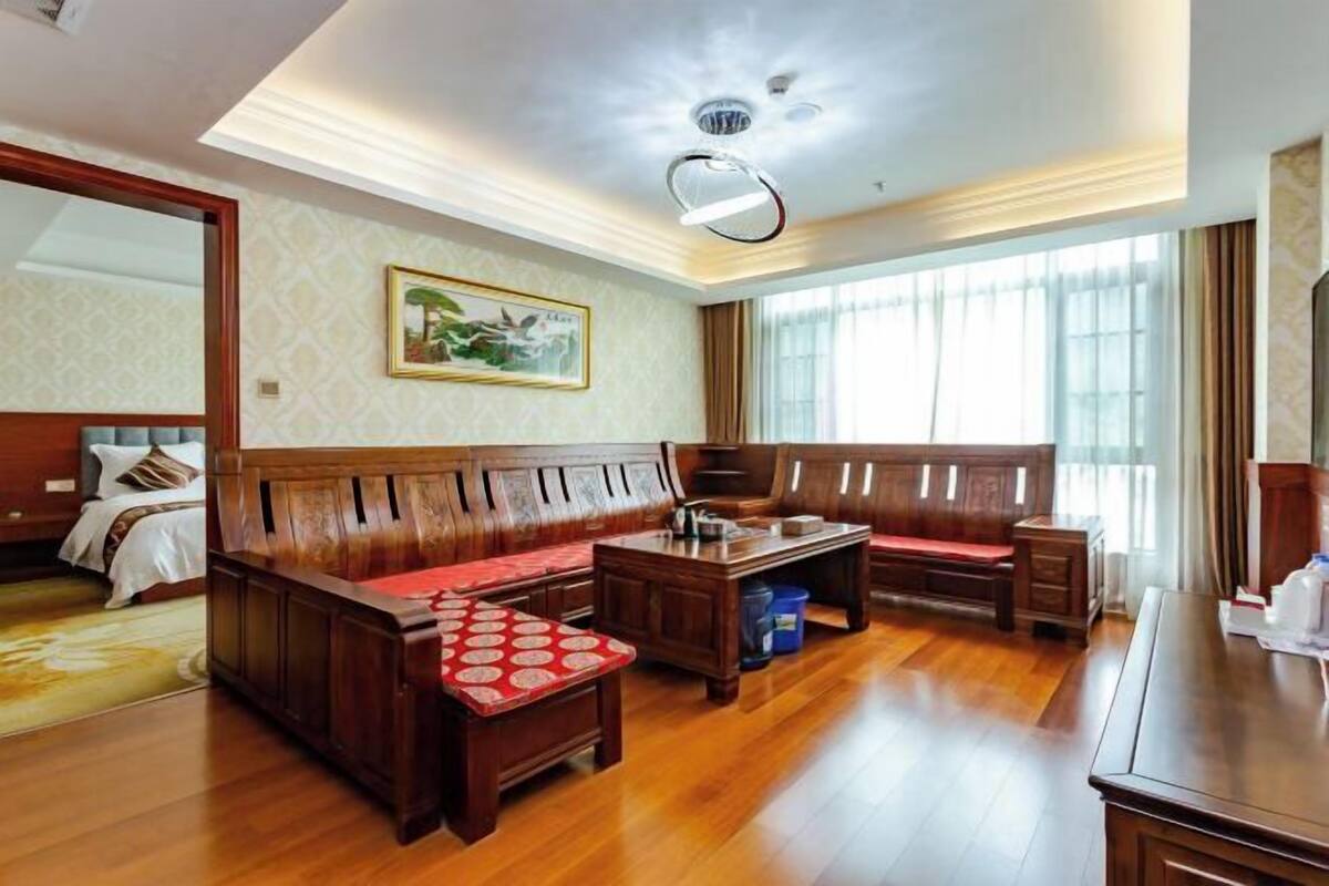 A spacious room with a wooden bench, a small table, and a bed with a headboard.