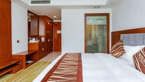 Habitación de hotel con una cama grande, armario de madera y un banco.