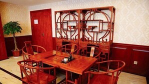 Un conjunto de comedor de madera tradicional con una mesa y seis sillas, un separador de ambientes de madera decorativo y una planta en maceta en un rincón.