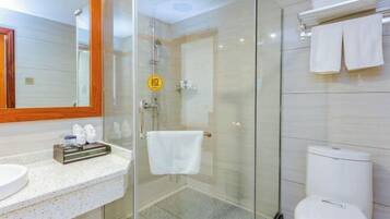 A modern bathroom with a glass shower enclosure, a white toilet, and a sink with a towel rack.
