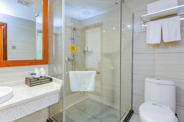 A modern bathroom with a glass shower enclosure, a white toilet, and a sink with a towel rack.