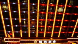 Fachada de hotel con líneas verticales iluminadas y un cartel en un idioma extranjero.