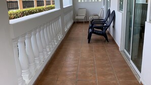 A covered balcony with tiled flooring, white balustrades, and two chairs. - Spacious apartment with sea views, everything you need to spend your vacations. (Isabela)