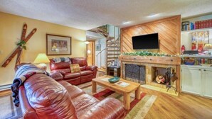 Ein gemütliches Wohnzimmer mit Kamin, Ledersofa und einer Treppe zu einer oberen Ebene.