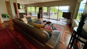 Uma sala de estar moderna com um sofá de couro, uma mesa de centro de vidro e uma grande janela com vista para o exterior.