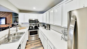 A modern kitchen with white cabinets, stainless steel appliances, and a wooden floor. - 3 Bedroom Condo in Keystone - West Keystone (Keystone)